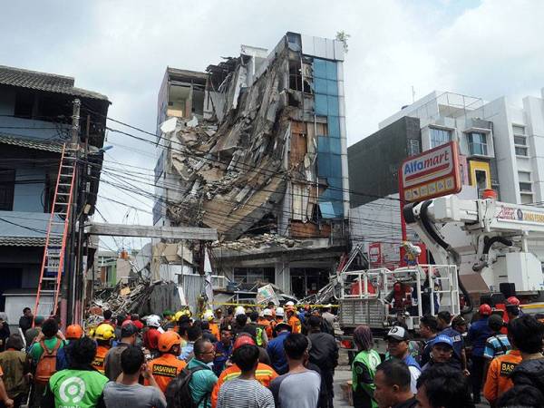 Orang ramai berkumpul di hadapan sebuah bangunan lima tingkat yang sebahagiannya runtuh dalam kejadian di Jawa Barat hari ini. - AFP