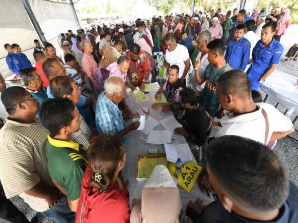 Petani dan peladang menyemak nama masing-masing pada Majlis Bantuan Tabung Bencana Tanaman Padi Akibat Taufan Lekima Kepada Peladang di Kawasan MADA yang diadakan di PPK MADA Kodiang hari ini. - Foto Bernama