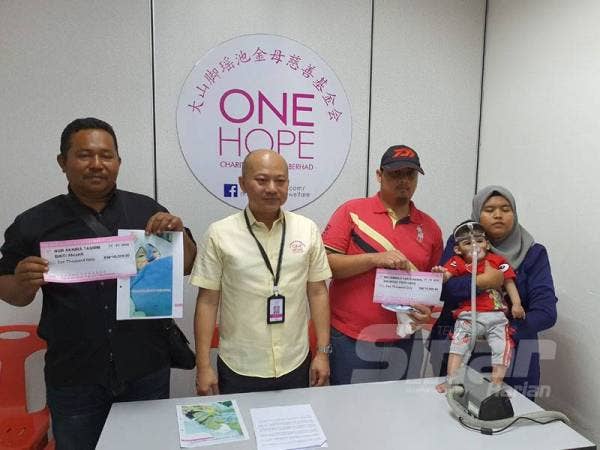 Sui Hui (tengah) memberikan bantuan awal sebanyak RM10,000 kepada keluarga kedua-dua bayi yang menglami masalah jantung.