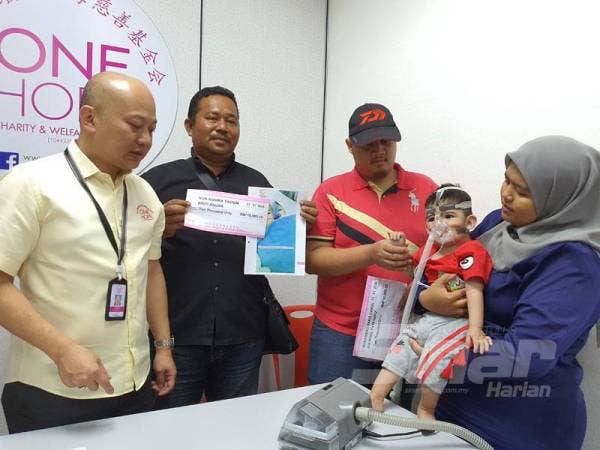 Sui Hui (kiri) melihat keadaan Muhammad Hariz yang perlu menggunakan mesin bantuan penafasan setiap masa.