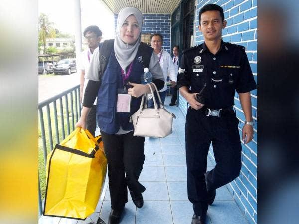 Petugas SPR (kiri) diiringi anggota polis membawa beg berisi peti undi untuk disimpan di Ibu Pejabat Polis Daerah Beaufort selepas Pusat Pengundian Awal Pilihan Raya Kecil Parlimen Kimanis di Bilik Gerakan Balai Polis Membakut ditutup pada 12 tengah hari hari ini. - Foto