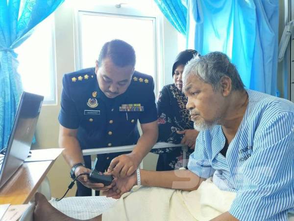 Timbalan Ketua Bahagian Pendaftaran JPJ Kedah, Iskandar Zulkarnain Mohamad Ali (kiri) sedang mengimbas cap jari Othman di HSB di sini, hari ini.