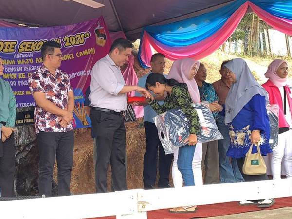 Siew Fook menyampaikan sumbangan persekolah kepada pelajar kurang berkemampuan sempena program tersebut di Kampung Chennah di sini hari ini.