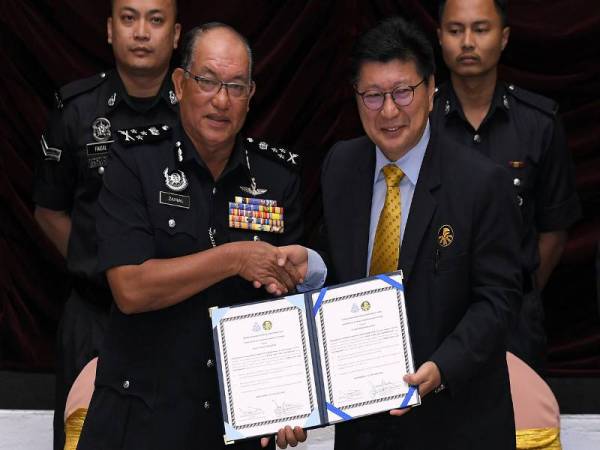 Zainal Abidin (depan dari kiri) menerima dokumen yang telah ditandatangani dari Thian Lai (depan dari kanan) pada Majlis Menandatangani Dokumen Kerjasama Tanggungjawab Sosial Korporat di Maktab PDRM hari ini. Foto: Bernama