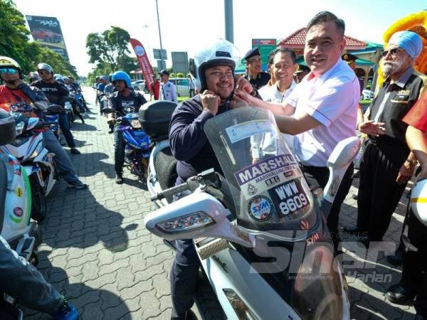 Siew Fook mengetatkan topi keledar salah seorang pengguna jalan raya pada majlis pelancaran Ops Bersepadu dan Kempen Keselamatan Jalan Raya Peringkat Kebangsaan sempena Perayaan Tahun Baru Cina di R&R Tapah, hari ini.