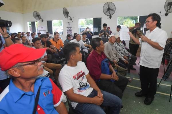 Mohd Shafie Apdal (kanan) menunjukkan dokumen minit mesyuarat Suruhanjaya Siasatan Diraja mengenai pendatang asing di Sabah kepada penduduk kampung ketika berkempen bagi Pilihan Raya Kecil Parlimen Kimanis di Kampung Bambangan, Membakut hari ini. - Foto: Bernama