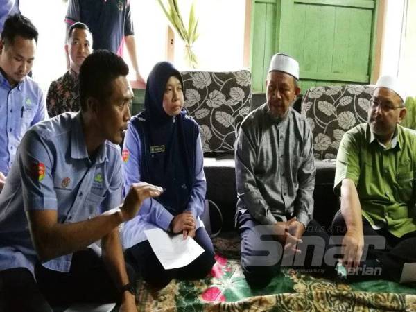 Farihah (dua kiri) dan wakil Perkeso Terengganu menerangkan tentang bantuan yang akan diterima keluarga arwah, kepada Wan Sukairi (kanan) dan Maliaman (dua kanan).