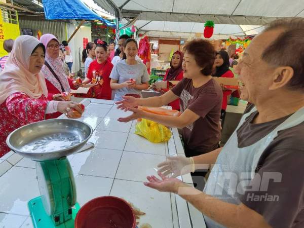 Zuraida mengedarkan buah limau ketika beramah mesra dengan pengunjung dan peniaga pada program Walkabout Tahun Baru Cina DUN Bukit Antarabangsa dan Parlimen Ampang di Pasar Pekan Ampang di sini pagi tadi