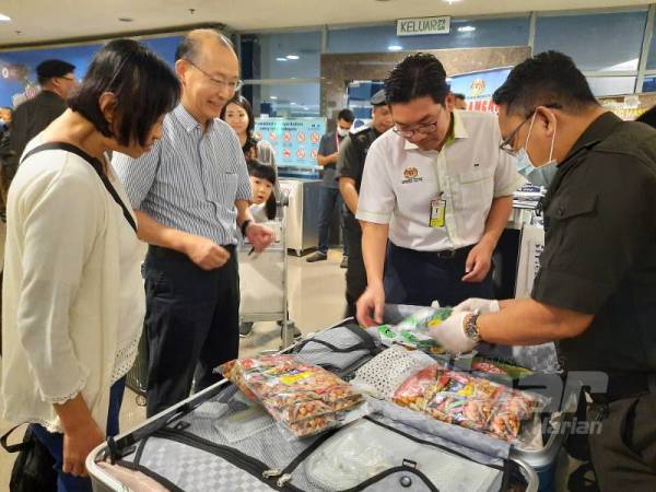 Tze Tzin (dua dari kanan) bersama pegawai Maqis memeriksa bagasi pelancong luar di LTAPP, Bayan Lepas semalam.