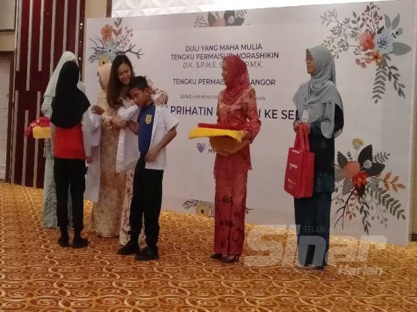 Tengku Permaisuri Norashikin berkenan memakaikan pakaian sekolah kepada salah seorang penerima.