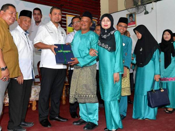 Menteri Besar Johor Datuk Dr Sahruddin Jamal menyerahkan geran hak milik tanah kepada wakil Ketua Blok 8 Felda Lok Heng Selatan Sumari Jadi, 56, dan isterinya Ngatinam Karchin, 54, pada Majlis Penyerahan Geran Hak Milik Tanah Felda Lok Heng Selatan di Dewan Terbuka Felda Lok Heng Selatan hari ini. - Foto Bernama