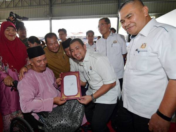 Menteri Besar Johor, Datuk Dr Sahruddin Jamal menyerahkan geran hak milik tanah kepada Peneroka Abas Ariff, 66, pada Majlis Penyerahan Geran Hak Milik Tanah Felda Lok Heng Selatan di Dewan Terbuka Felda Lok Heng Selatan hari ini. - Foto Bernama