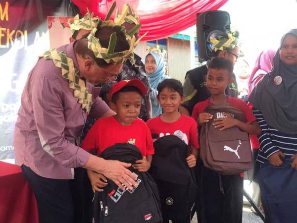 Anwar menyampaikan sumbangan beg sekolah kepada anak orang asli di Kampung Orang Asli Sunggala dekat sini hari ini.