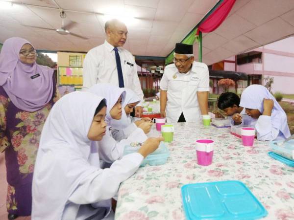 Abdul Aziz (kanan) ketika meninjau pengambilan sarapan pagi percuma di SK Datin Khadijah hari ini.