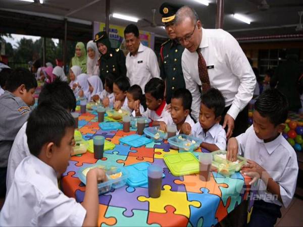 Azmi (berdiri dari kanan) beramah mesra bersama murid yang menikmati sarapan pagi dalam program penambahbaikan RMT di SK Jeram Batu 20, di sini, hari ini.