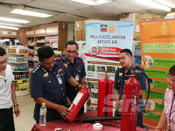 Mohamad Shoki (dua dari kiri) memeriksa alat pemadam api di pasar raya The Store hari ini.