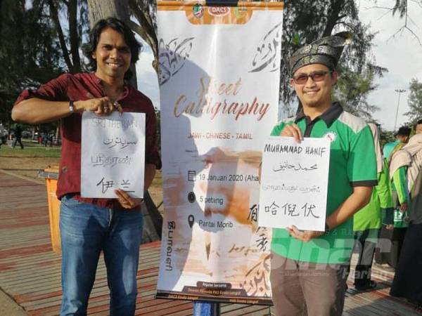 Ketua Pemuda MIC Selangor, Sritheran Renganathan dan Setiausaha Pemuda Pas Negeri Selangor, Muhammad Hanif Jamaluddin menunjukkan nama masing-masing yang ditulis dengan empat jenis tulisan.