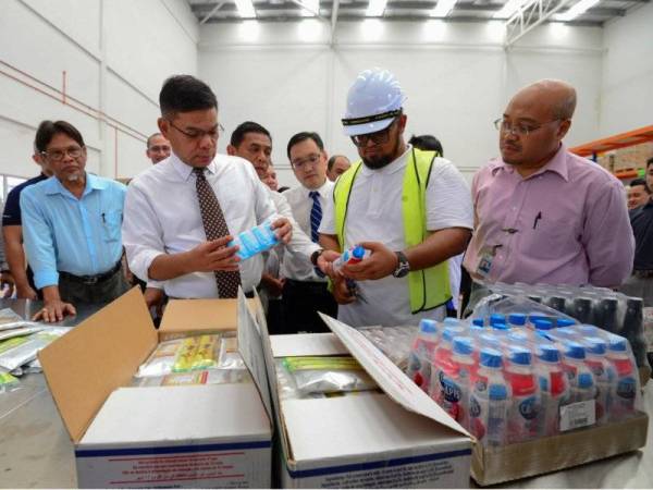 Saifuddin Nasution(tiga dari kiri) meneliti makanan dan minuman yang ada di gudang Food Bank Malaysia pada Majlis 'Soft Launch' Pusat Pengumpulan Dan Pengagihan Program Food Bank Malaysia di Kawasan Perusahaan Bukit Angkat, Kajang hari ini.- FOTO: BERNAMA