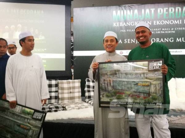 Fadzil (kanan) menyampaikan cenderahati kepada Presiden Pembela, Aminuddin Yahaya yang turut hadir pada Pra Pelancaran Malakat Mall Cyberjaya di sini malam tadi.