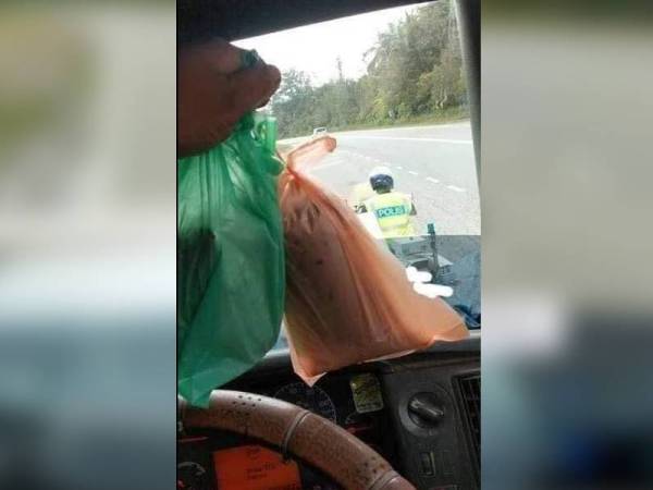 Polis membeli air dan makanan buat pemandu lori terkandas di Jalan Bayam di sini.