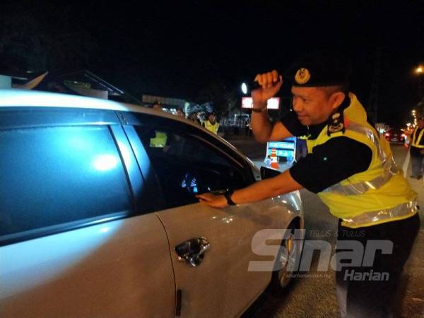 Ismasuhaimi sedang memeriksa kenderaan yang berhenti di sekatan jalan hadapan Masjid Aman dalam Ops Tahun Baru Cina 2020 malam tadi.