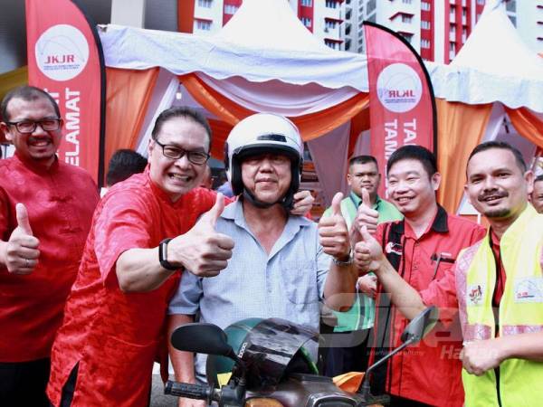 Azizul Azily (dua dari kiri) dan Yau Duenn (dua dari kanan) menghadiahkan topi keledar baharu kepada seorang penunggang motosikal di BHPetrol Jalan Cheras 1 & 2, Kuala Lumpur. - Foto: ZAHID IZZANI