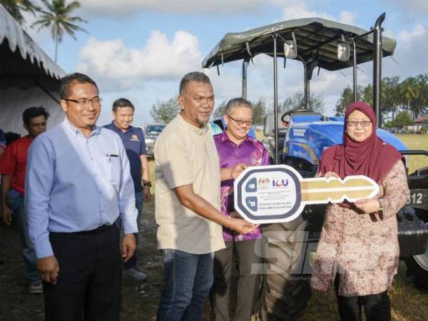 Fuziah (kanan) ketika acara simbolik penyerahan kunci traktor kepada penduduk.