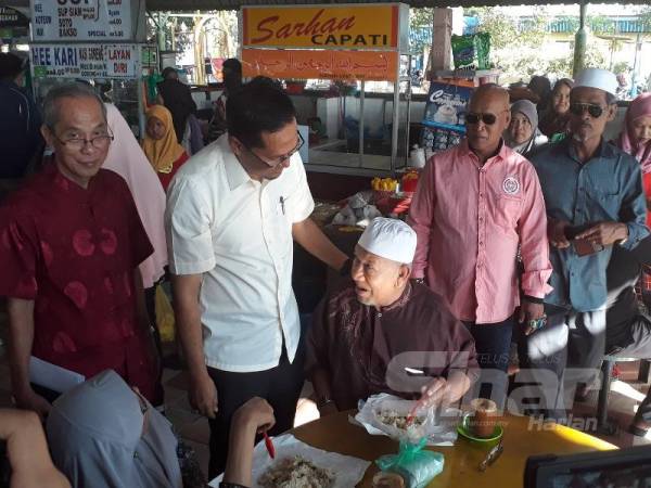 Mohd Asmirul (dua dari kiri) menyantuni penduduk yang datang bersarapan di Medan Selera Bilion hari ini.
