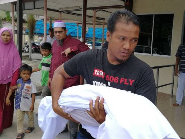 Taquddin memangku jenazah anaknya selepas selesai proses bedah siasat.