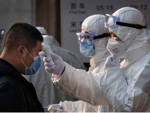 Petugas kesihatan memeriksa suhu orang awam wanita bagi menangani penularan wabak koronavirus. Foto: Getty Images