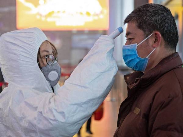 Petugas kesihatan memeriksa suhu badan penumpang di Nanjing, China. -Foto EPA