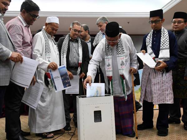 Azmi Abdul Hamid ketika meletakkan kertas Pelan Damai Israel-Palestin yang dibuat Presiden Amerika Syarikat Donald Trump sebagai gimik menolak pelan itu selepas sidang media di sebuah hotel hari ini. - Foto Bernama