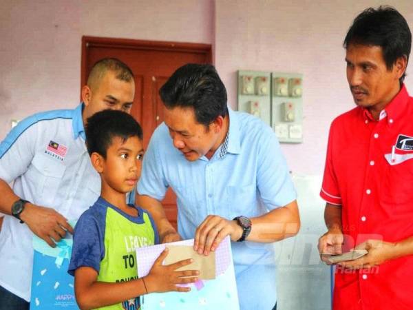 Bob Manolan (tengah) ketika menyampaikan sumbangan kepada pelajar orang asli di perkampungan tersebut.