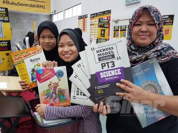 Rohana bersama dua anaknya menunjukkan buku latih tubi yang diborong keluarganya pada Jualan Gudang Awal Tahun Karangkraf di Shah Alam semalam.
