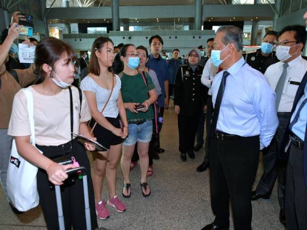 Muhyiddin (dua dari kanan) bertanya sesuatu kepada orang ramai yang masuk ke Singapura ketika meninjau langkah-langkah yang dibuat bagi mencegah penularan jangkitan koronavirus di Kompleks Kastam, Imigresen dan Kuarantin (CIQ) di Bangunan Sultan Iskandar (BSI) hari ini. -Foto Bernama