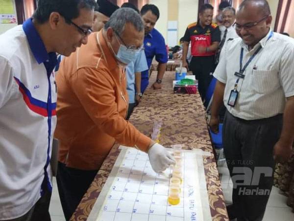 Aminolhuda (dua dari kini) memeriksa peralatan ujian saringan air kencing di SMK Tunku Putra, Tongkang Pechah semalam.