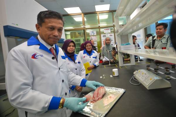 Munir (kiri) menunjukkan demonstrasi pensampelan ikan di Pusat Biosekuriti Perikanan Kuala Lumpur semalam.