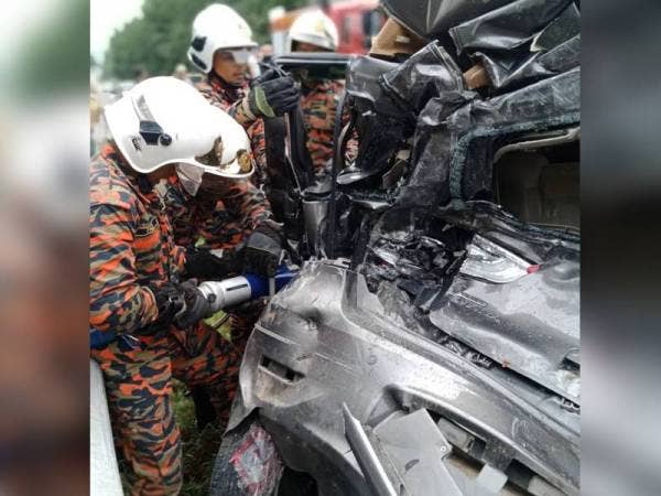 Anggota bomba dari Balai Bomba dan Penyelamat Muadzam Shah menggunakan alat pemotong untuk memotong bahagian kenderaan yang remuki bagi mengeluarkan mangsa yang tersepit selepas terbabit kemalangan di Kilometer 100, Jalan Kuantan-Segamat, Muadzam Shah, petang semalam. FOTO: IHSAN BOMBA