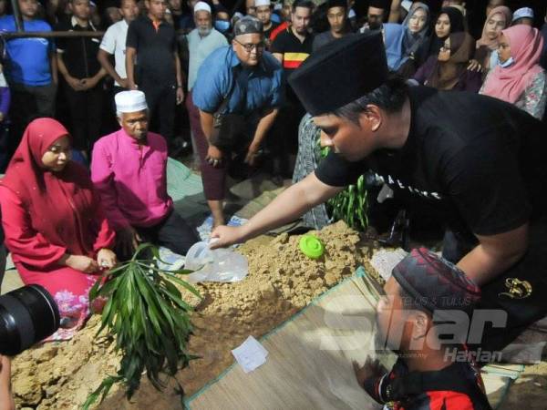 Ahli keluarga menyiram air ke pusara Allahyarham Abam selepas selesai dikebumikan di Tanah Perkuburan Islam Jalan Sungai Pusu. -Foto Sinar Harian ROSLI TALIB