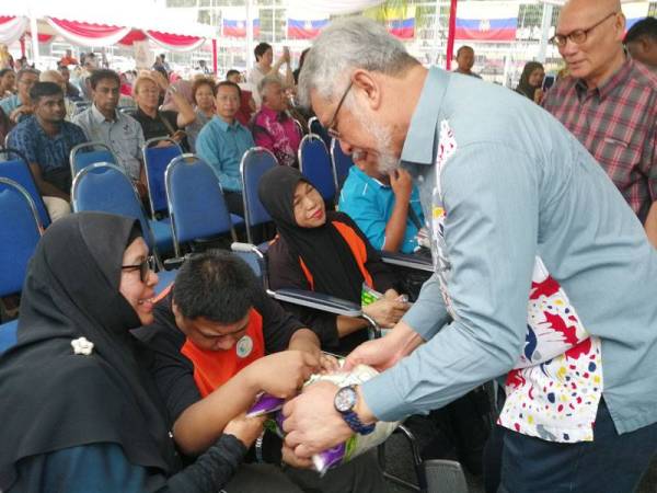 Khalid menyampaikan bantuan makanan kepada salah seorang penduduk Perumahan Awam Seri Perak pada majlis perasmian Kempen Kita.