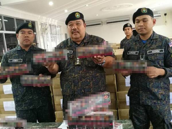 Azizan (tengah) menunjukkan rokok yang dirampas dalam serbuan itu.