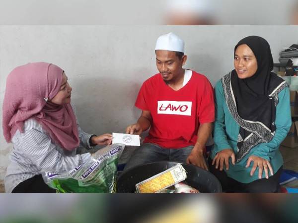 Rukiza (kiri) menyampaikan sumbangan daripada SCB kepada Zulkifli yang tidak mampu lagi untuk bekerja.