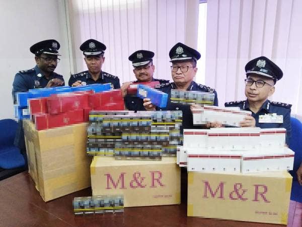 Paddy (dua dari kanan) bersama pegawainya menunjukkan sebahagian rokok seludup yang dirampas.