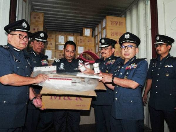Paddy (kiri) bersama pegawainya menunjukkan sebahagian rokok seludup yang dirampas.