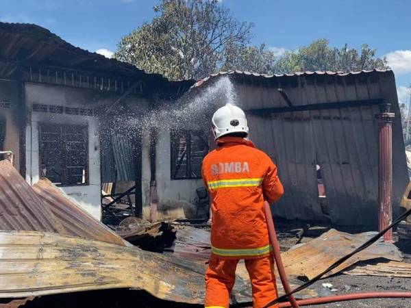 Anggota bomba memadamkan kebakaran yang meragut nyawa seorang warga emas di Kampung Batas Lintang, Simpang Empat hari ini.