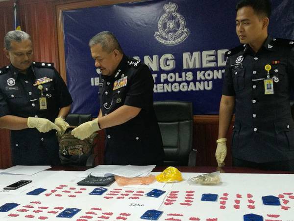 Roslee (tengah) menunjukkan beg yang menyimpan dadah jenis methamphetamine yang disimpan di dalam lubang yang ditimbus tanah oleh suspek.