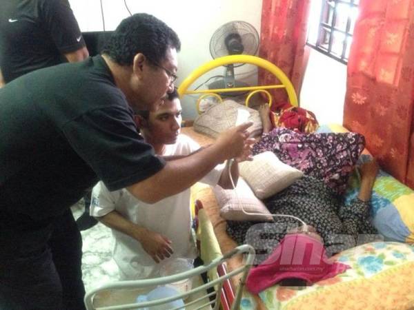 Ungku Sulaiman (kanan) membantu anaknya Ungku Muhammad Danial memasukkan susu melalui tiub di hidung Zaleha.