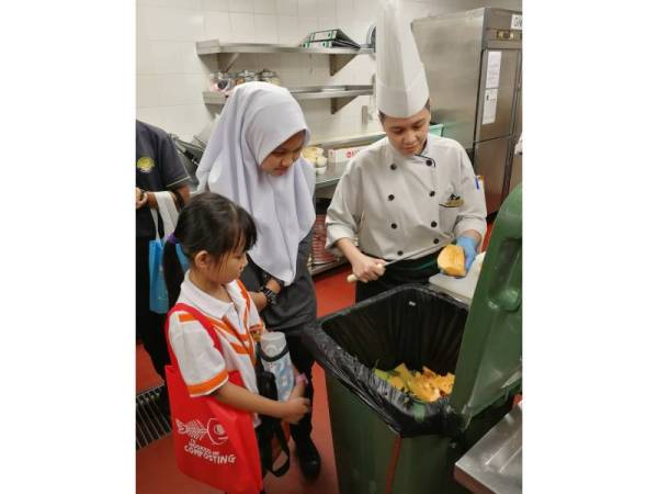 PELAJAR yang mengikuti program #sunwayforgood #zerofoodwastage melihat cara pembuangan sisa makanan sebelum diproses menggunakan mesin kompos.