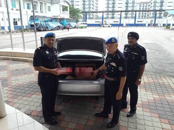 Rosman (tengah) menunjukkan pelbagai jenis rokok tidak bercukai dalam but kereta suspek.