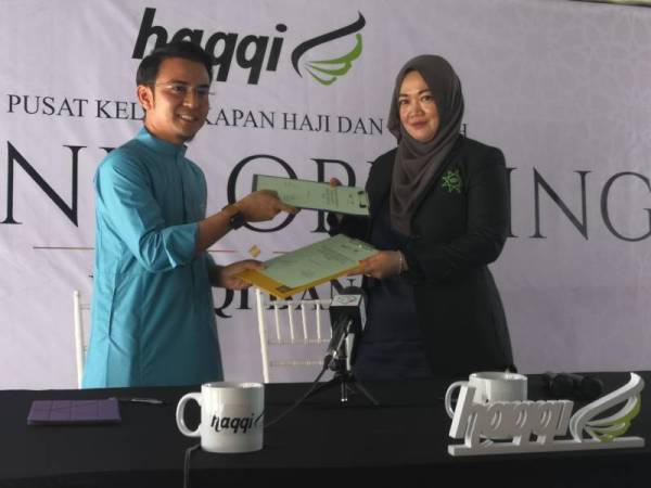 MOHAMAD Fitri (kiri) dan Noorsamah bertukar-tukar dokumen memorandum persefahaman pada majlis pelancaran Butik Haqqi 2020 di Bandar Baru Bangi pada hari ini.